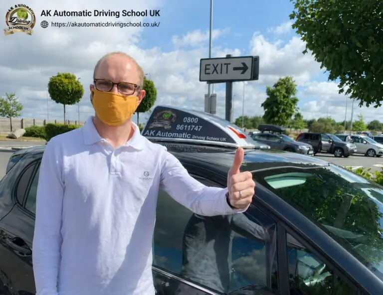 AK Automatic Driving School pupil giving a thumbs up beside the training car