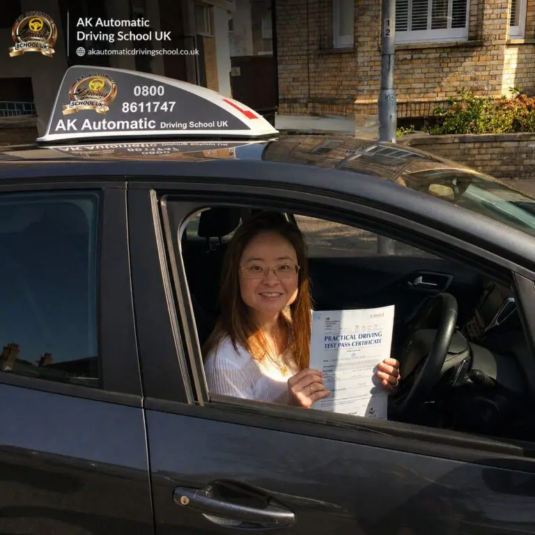AK Automatic Driving School pupil holding a practical driving test pass certificate from the car window