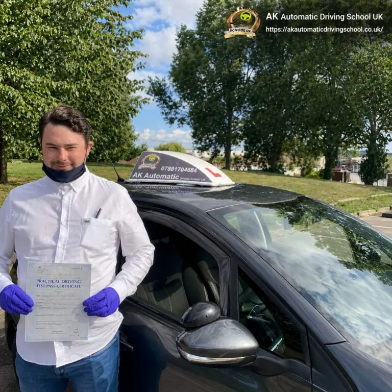 AK Automatic Driving School pupil holding a practical driving test pass certificate beside the instructor car