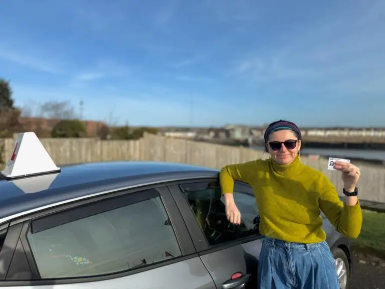 AK Automatic Driving School pupil beside the instructor car holding a driving licence